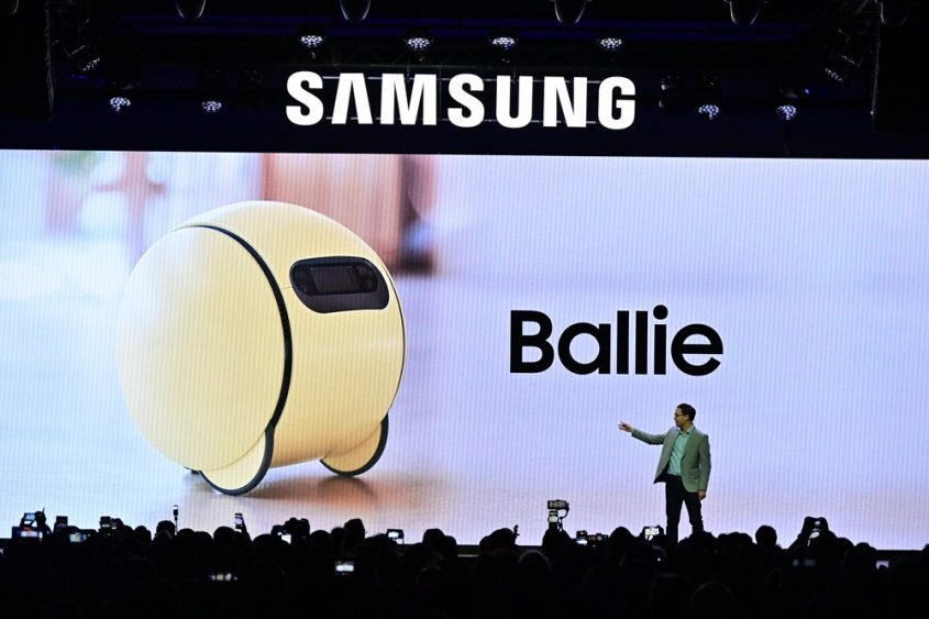 A person standing on stage with a large screen

Description automatically generated